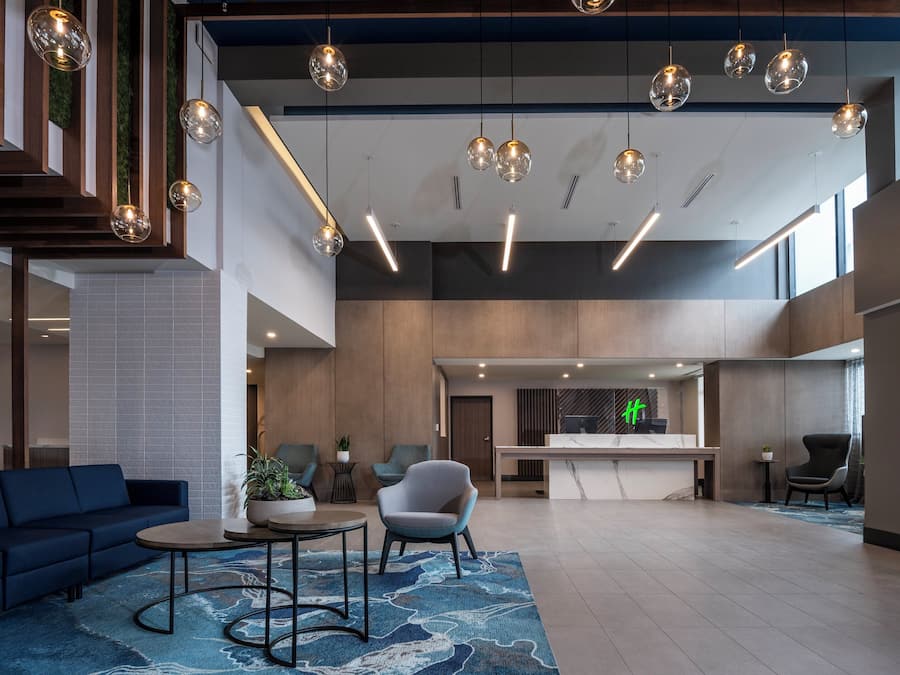 A modern hotel lobby with a reception desk, seating area, and a large open space with a high ceiling and hanging spherical lights.