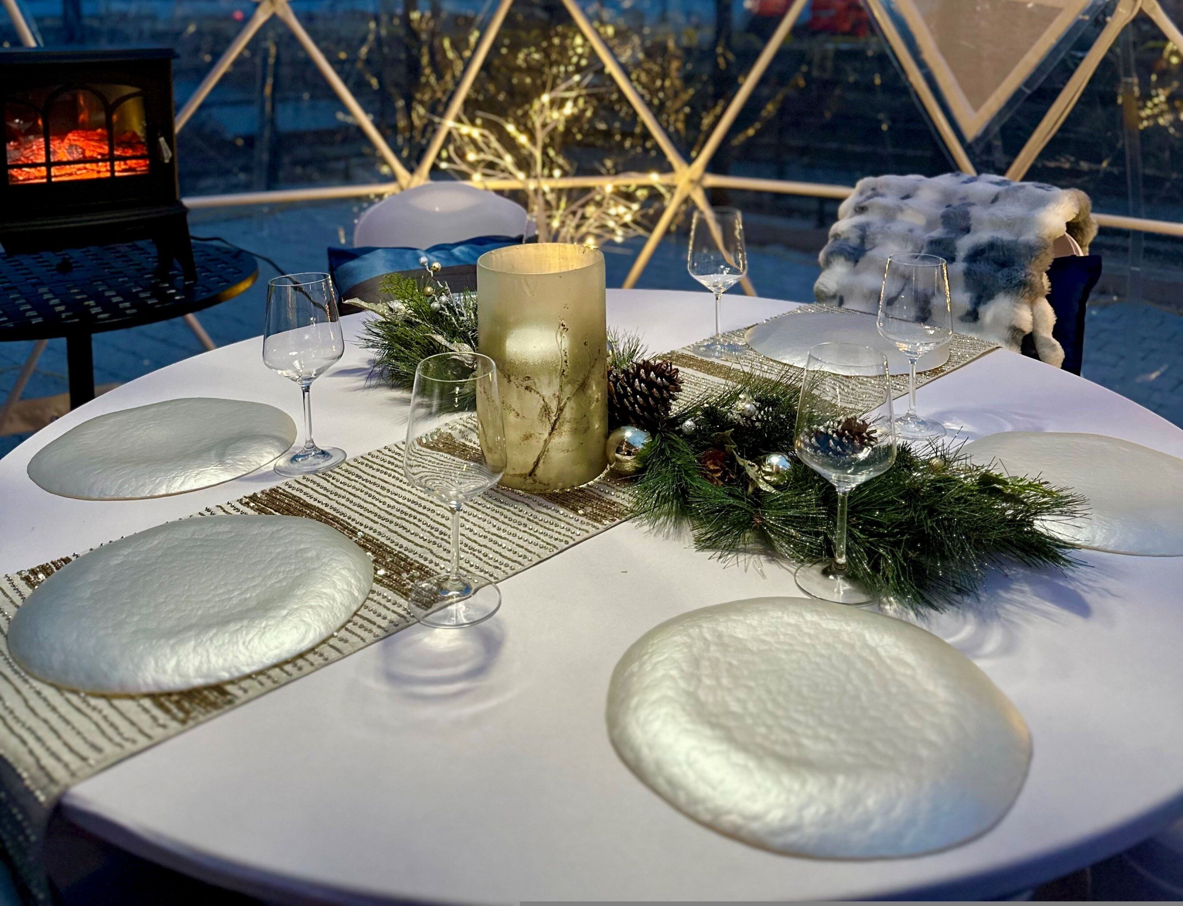 A table set for a meal with a candle centerpiece, glasses, and festive decorations.