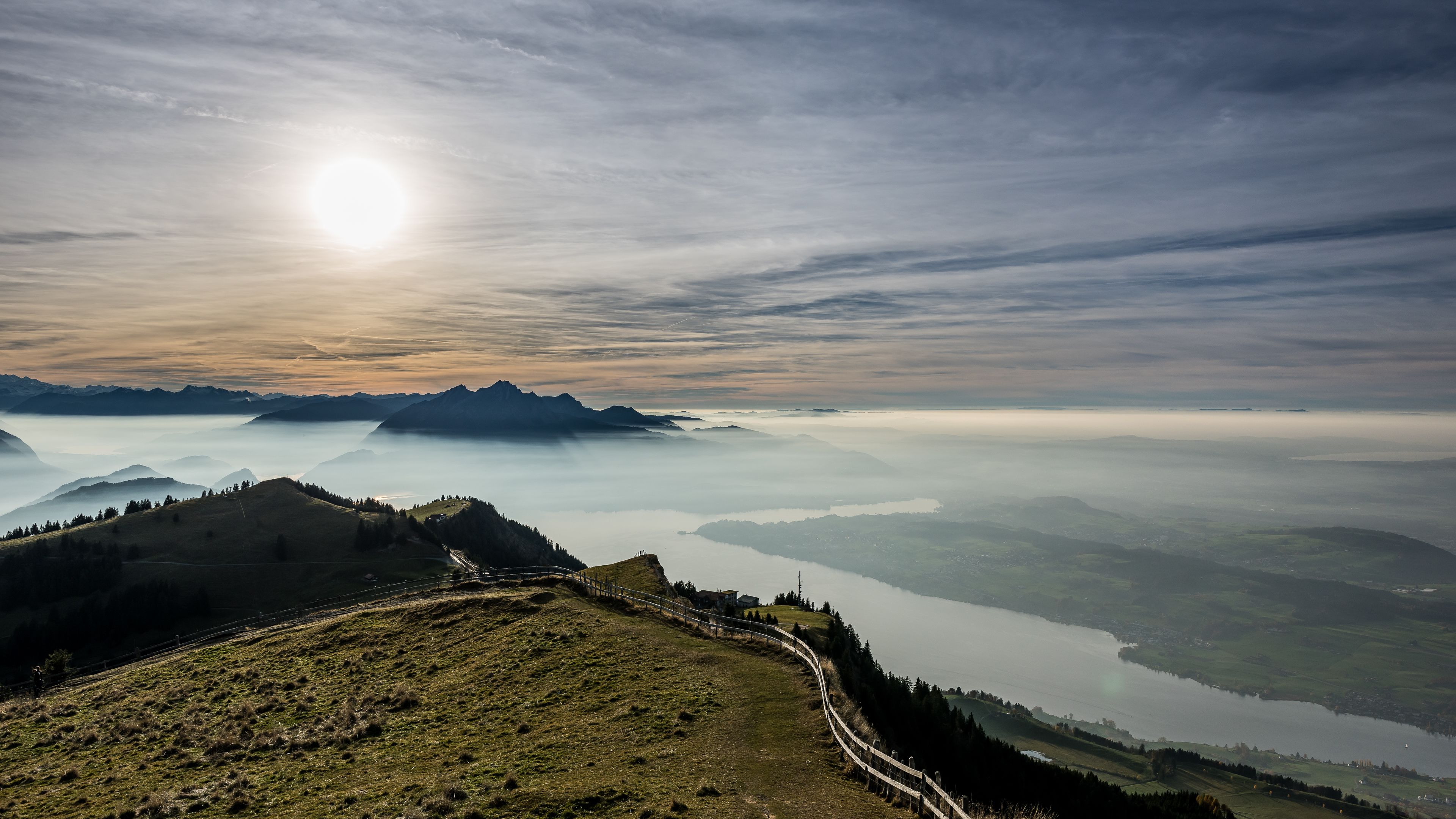 Vista panorámica de un paisaje montañoso con un lago y un sendero sinuoso.