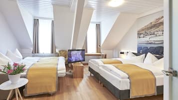 Een hotelkamer met twee bedden, een televisie, een klein tafeltje en een raam met gordijnen.
