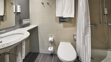 A modern bathroom with a granite sink, toilet, and shower.