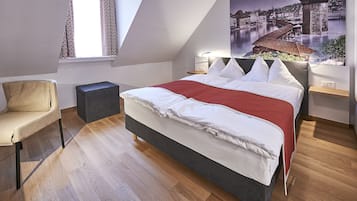 A bedroom with a bed, a chair, a nightstand, and a window with curtains.