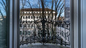 A wrought iron gate with intricate designs, leading to a building with a white facade and multiple windows. - Hotel Central Luzern (Lucerne)