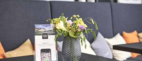 Una mesa con un florero y un anuncio enmarcado de una aplicación.
