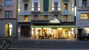 A restaurant with outdoor seating, a bike parked in front, and a building with a sign that reads 'dean & david.' - Hotel Central Luzern (Lucerne)
