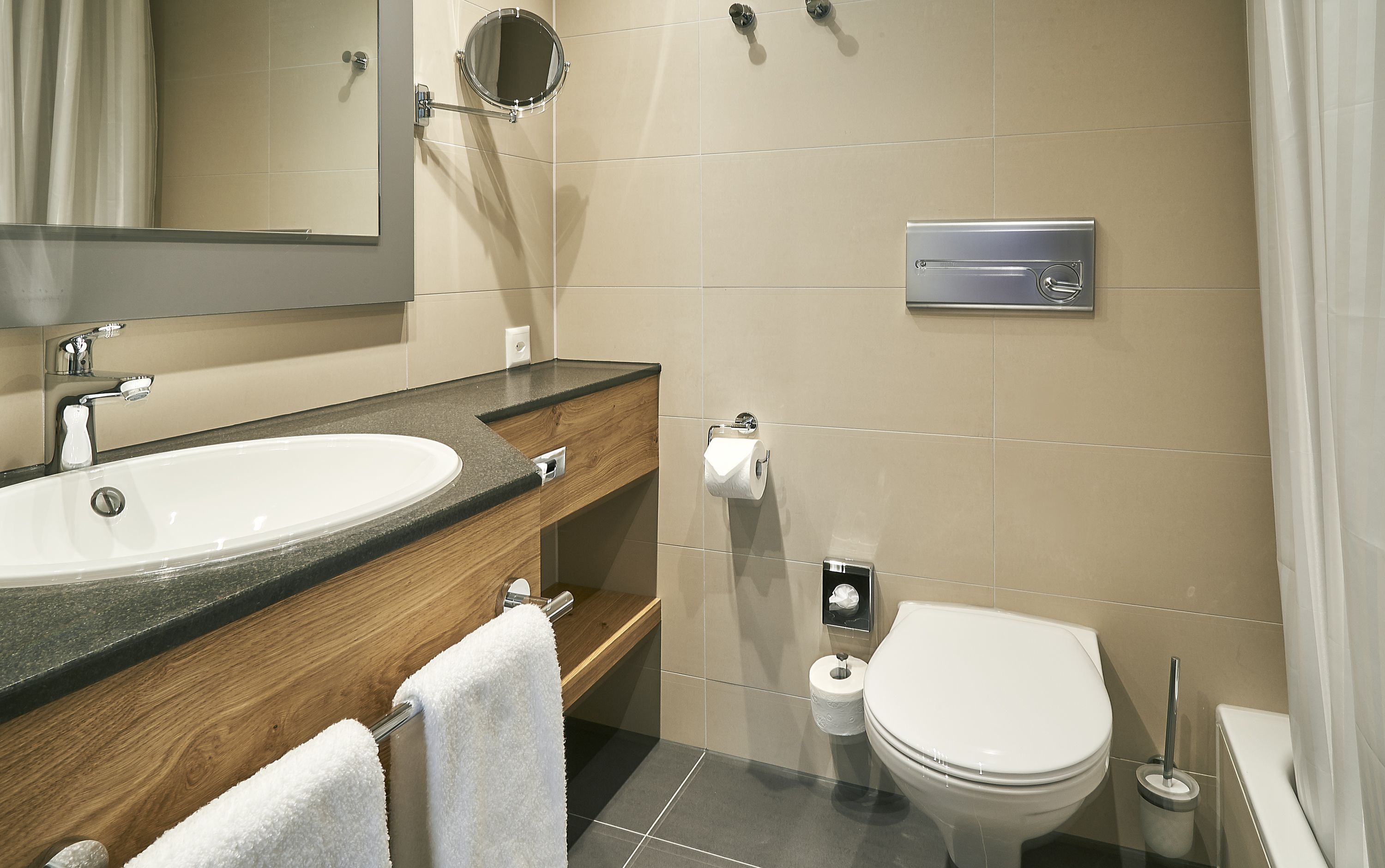 A modern bathroom with a large sink, mirror, toilet, and a towel rack.