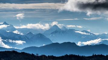 A mountainous landscape with snow-covered peaks and a forested valley.