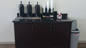 A bar area with a black countertop, multiple bottles, and a trash bin.