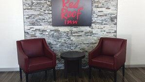 A Red Roof Inn sign with two red chairs and a small round table in front. - Red Roof Inn Fort Worth West (Fort Worth)