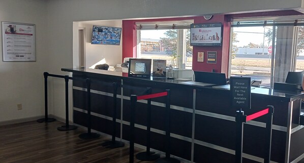 Zona de recepción con mostrador, una computadora y ventana con vistas al exterior.