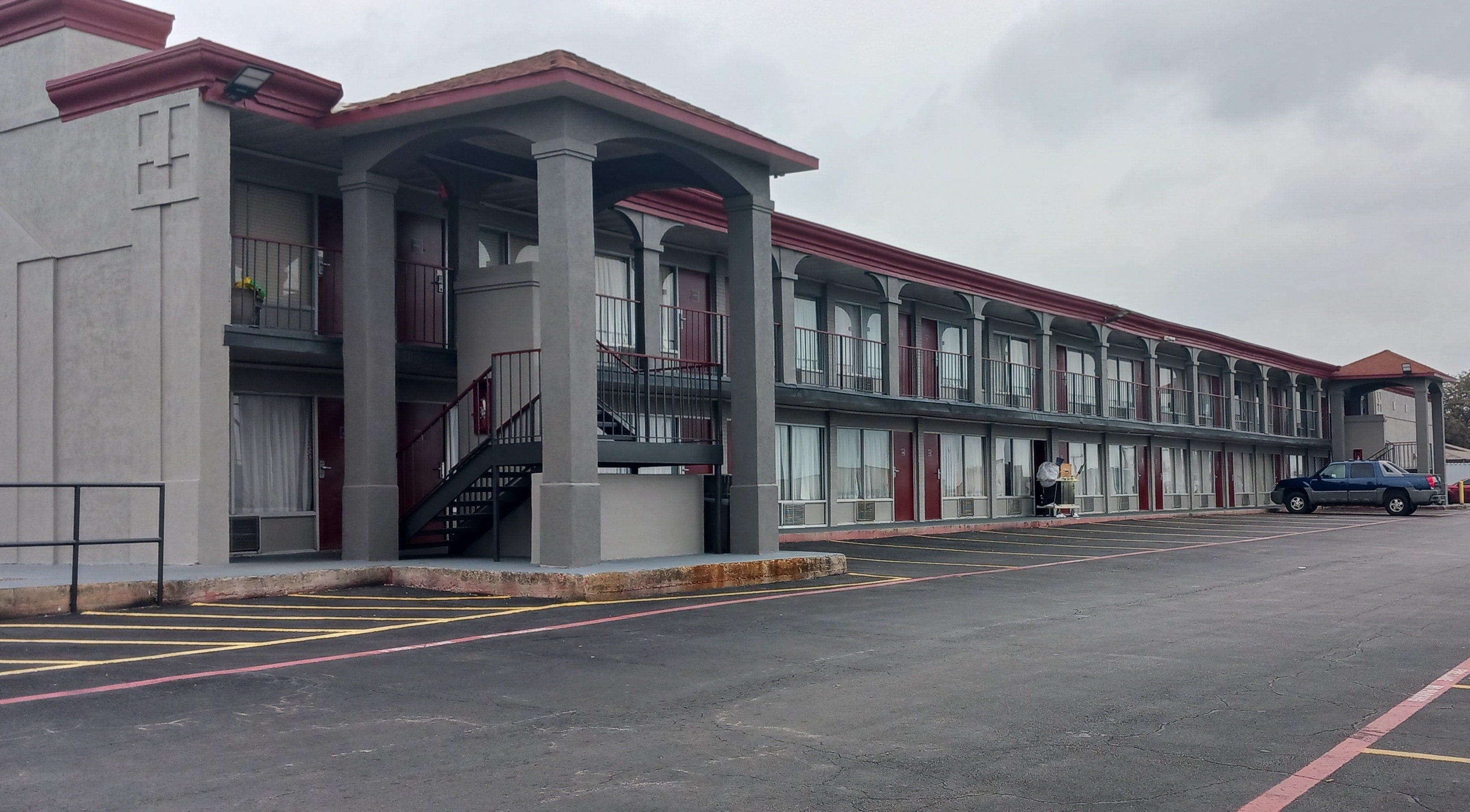 A multi-story motel with a central courtyard, individual room entrances, and a parking area.