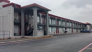 A multi-story motel with a central courtyard, individual room entrances, and a parking area.