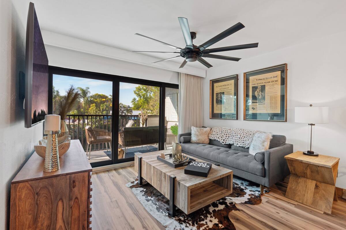 A modern living room with a grey sofa, wooden coffee table, and a ceiling fan.