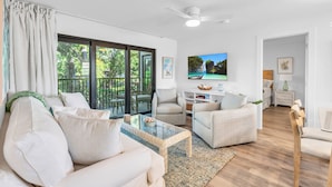 A modern living room with a sofa, armchairs, a coffee table, and a TV. - Park Shore Resort (Naples)