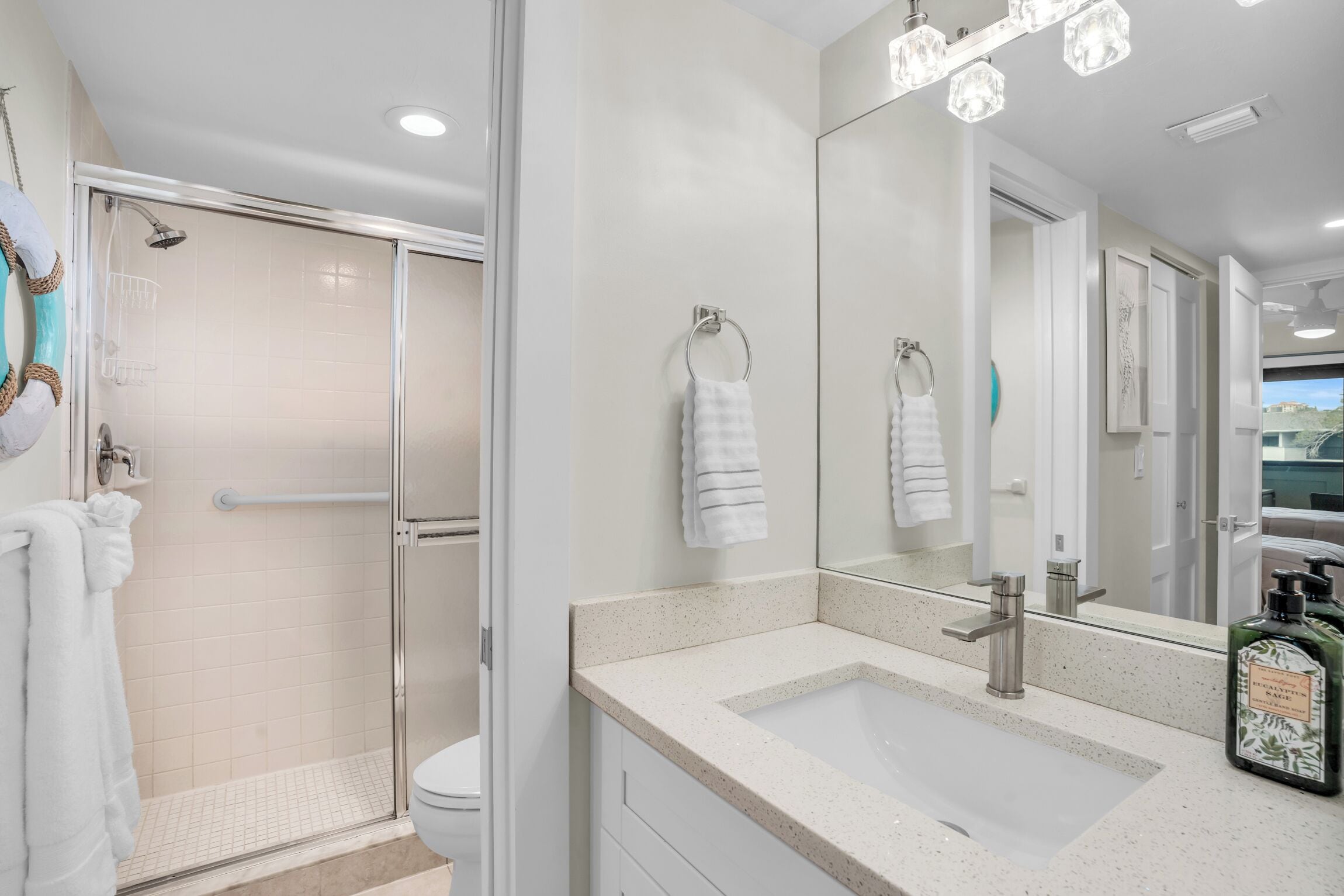 A modern bathroom with a glass-enclosed shower, a large mirror, and a countertop sink.