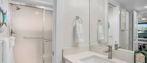 A modern bathroom with a glass-enclosed shower, a large mirror, and a countertop sink.