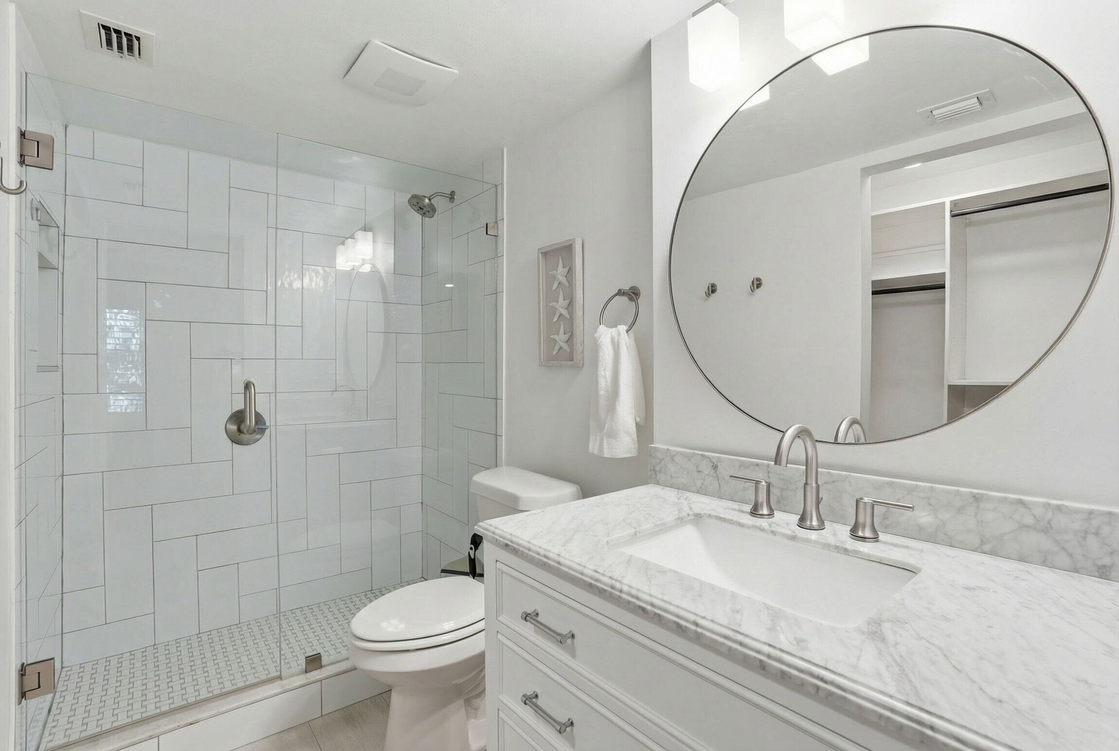 A modern bathroom with a shower, toilet, vanity, and a large mirror.