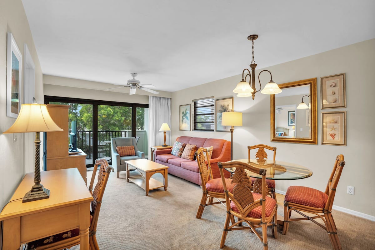 A well-lit living room with a sofa, chairs, a table, and a ceiling fan.