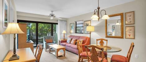 A well-lit living room with a sofa, chairs, a table, and a ceiling fan.