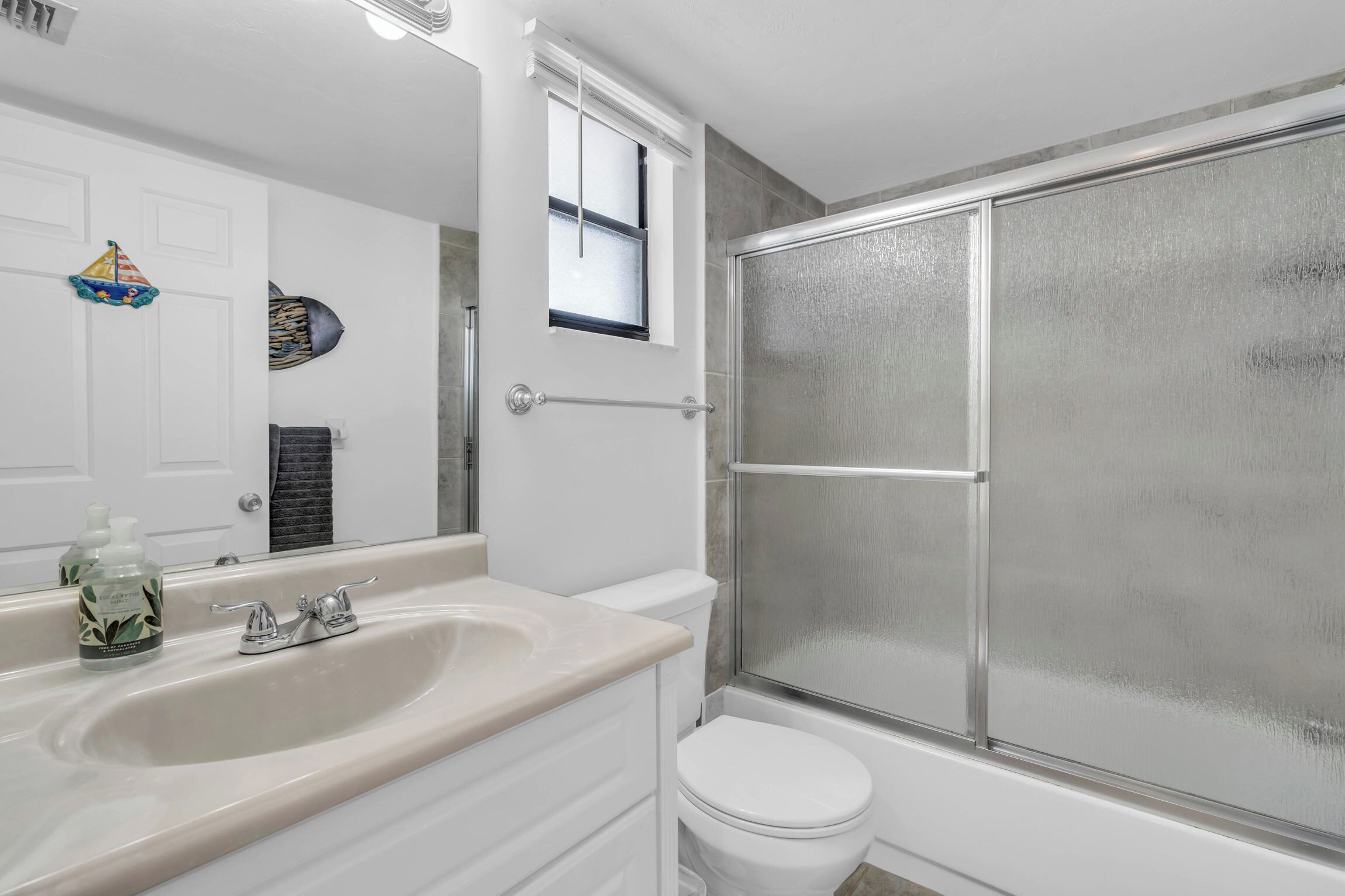 A bathroom with a white sink, a toilet, and a glass shower enclosure.