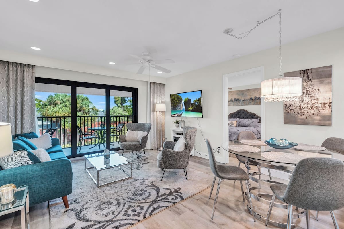 A modern living room with a sofa, armchairs, a coffee table, and a dining area with chairs and a table.