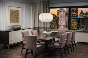 A dining room with a city view, a modern chandelier, and a decorative bowl on the table.