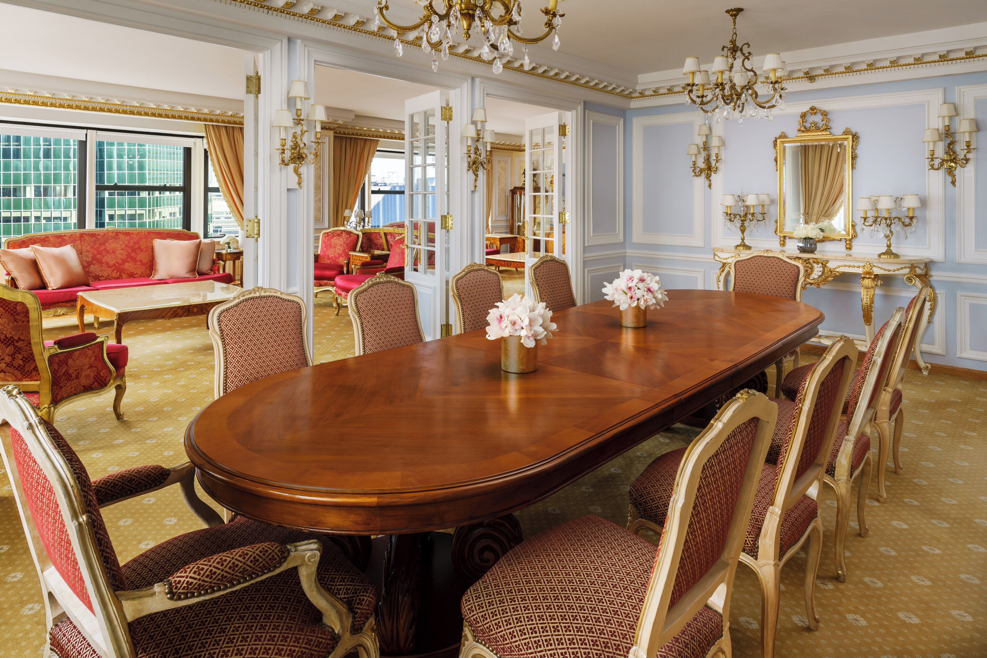 Un comedor formal con una gran mesa de madera, sillas ornamentadas y un candelabro.