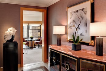 A modern kitchen with a built-in dishwasher, stainless steel appliances, and a glass-fronted shelving unit displaying decorative vases. at Lotte New York Palace