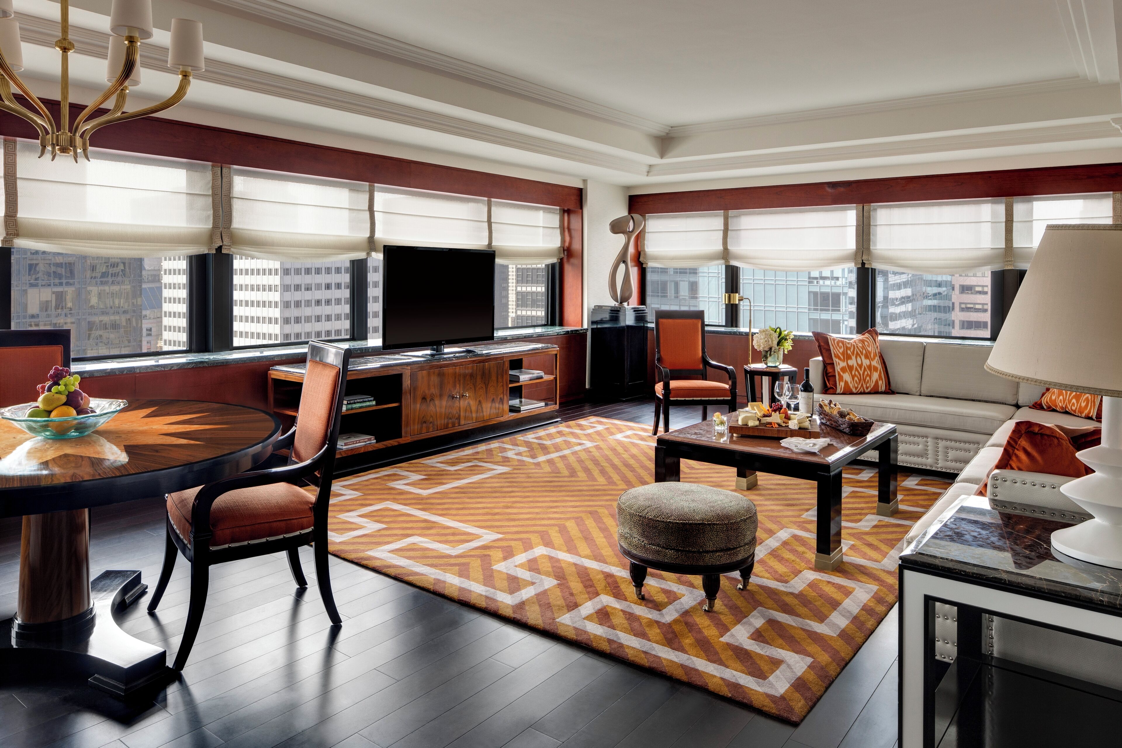 A modern living room with a large TV, seating area, and a city view.