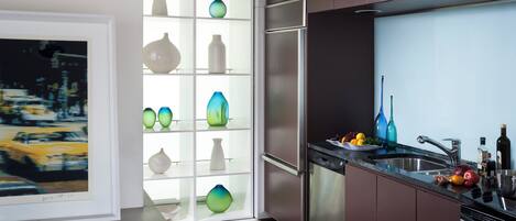 A modern kitchen with a built-in dishwasher, stainless steel appliances, and a glass-fronted display cabinet with decorative vases.