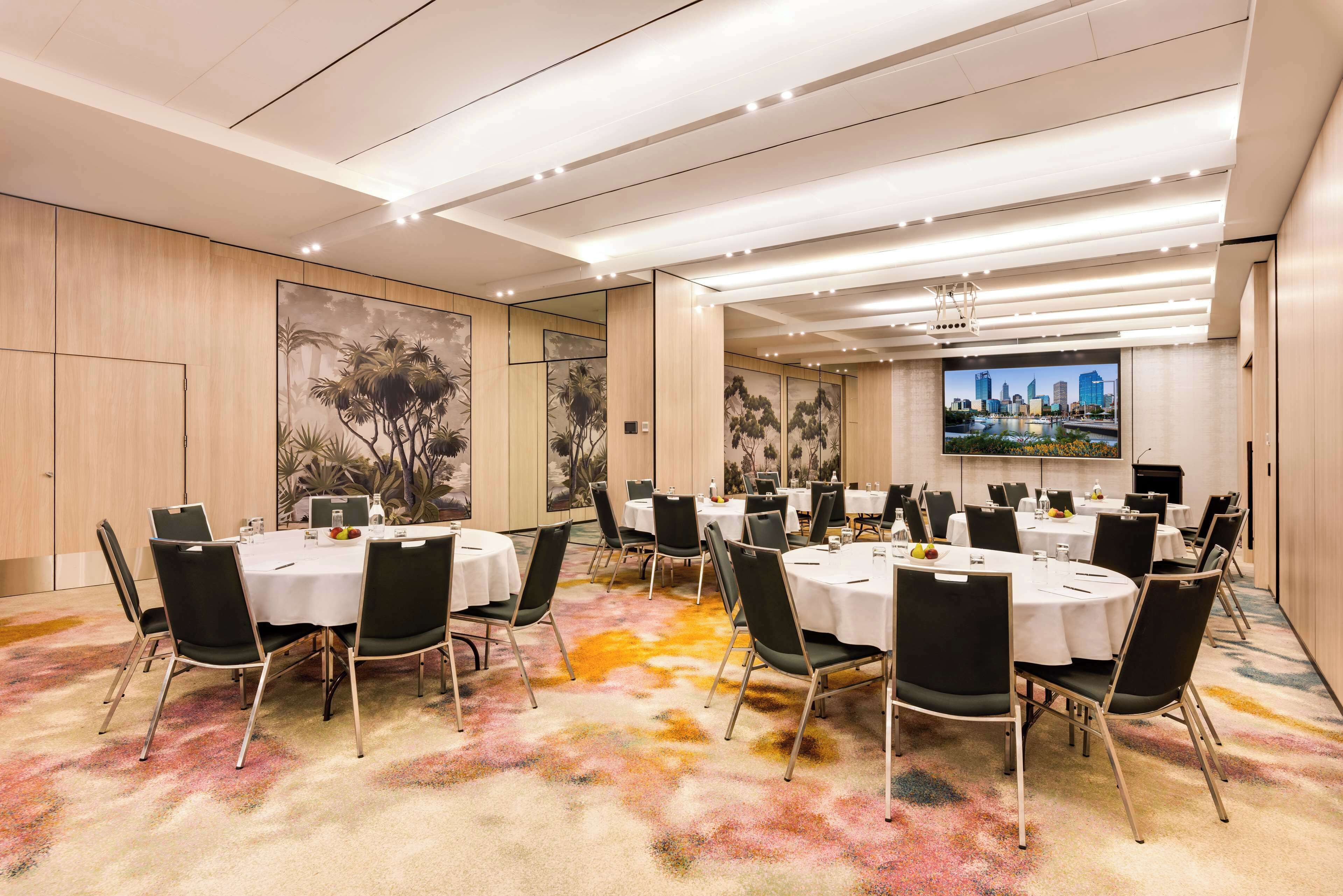 A conference room with round tables, black chairs, and a colorful carpet.