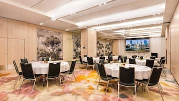 A conference room with round tables, black chairs, and a colorful carpet.
