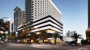 Un hotel moderno con un llamativo letrero de 'Pan Pacific', que presenta una estructura de varios pisos con fachada plana y una serie de balcones.