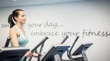 En person træner på et løbebånd i et fitnesscenter med motiverende tekst på væggen.
