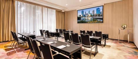 A conference room with a cityscape view, large windows, and a carpeted floor.