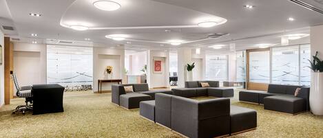 A spacious lobby with multiple seating areas, a reception desk, and large windows offering views.