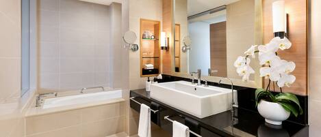 A modern bathroom with a large bathtub, a double sink vanity, and a mirror.
