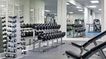 Un gimnasio con racks de pesas, mancuernas y equipo de ejercicio.