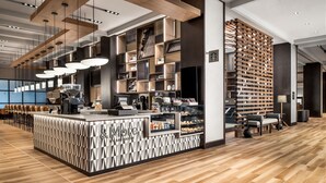 L'intérieur d'un café moderne présente un comptoir central, un espace salon et une variété de machines à café et de vitrines.