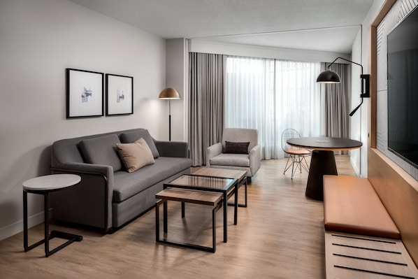 A modern living room with a sofa, coffee table, armchair, and a round dining table. - Sheraton Gateway Hotel In Toronto International Airport (Mississauga)