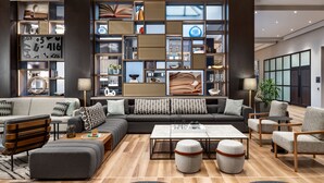Un salon moderne avec un canapé d’angle, une table basse et une bibliothèque remplie de livres et d’objets décoratifs.
