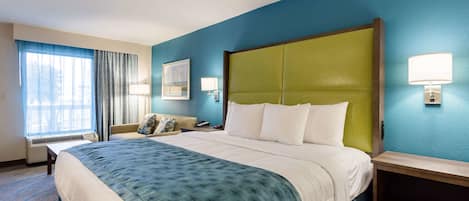 A hotel room with a large bed, a bedside table, a lamp, and a window with curtains.