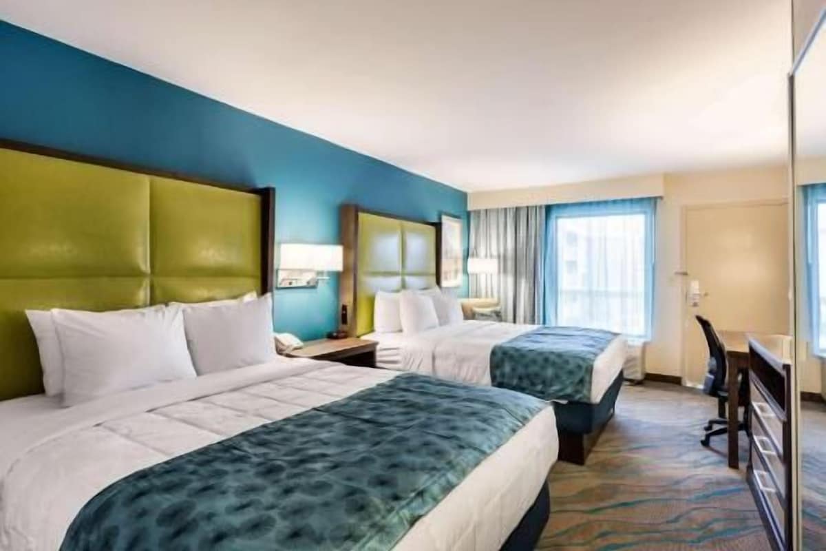 A hotel room with two beds, a desk, and a chair.