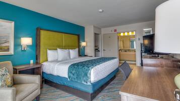 A hotel room with a bed, a desk, a chair, a nightstand, and a television.
