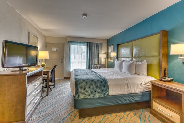 Una habitación de hotel con cama, escritorio, televisor y dos lámparas de noche.