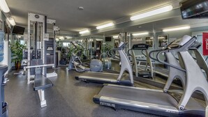 Un gimnasio con cintas de correr, máquinas de pesas y espejos.