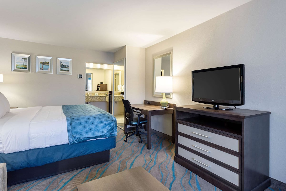 A hotel room with a bed, desk, television, and a bathroom visible in the background.
