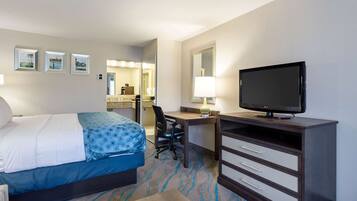 A hotel room with a bed, desk, television, and a bathroom visible in the background.