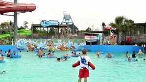 Un parque acuático con una piscina grande, flotadores inflables y un mural de personajes de dibujos animados.