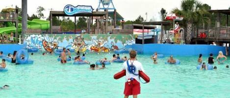 A water park with a large pool, inflatable tubes, and a mural of cartoon characters.
